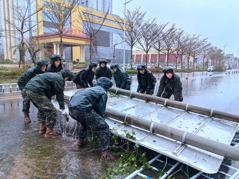武警海口支队官兵正在移除被风吹到的路边指示牌。房立摄