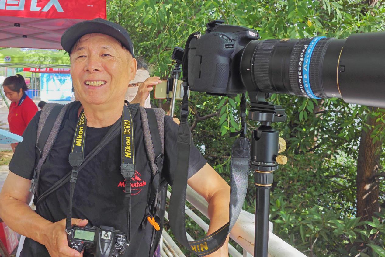 带着两台单反相机观看龙舟赛的宋大爷。 冷婷渟摄